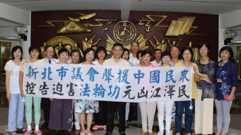 Коллективное фото депутатов Городского совета Нового Тайбэя. Надпись на плакате: «Новый Тайбэй поддерживает жителей Китая, подающих уголовные иски против Цзян Цзэминя, организатора преследования Фалуньгун»