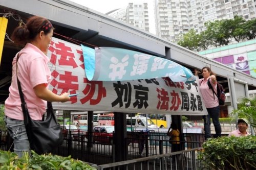 Члены Молодёжной ассоциации Гонконга (в розовых рубашках) пытались загородить плакат местных последователей Фалуньгун, используя свой плакат с клеветнической информацией