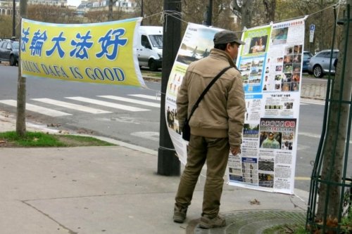 Туристы из Китая читают материалы о Фалуньгун