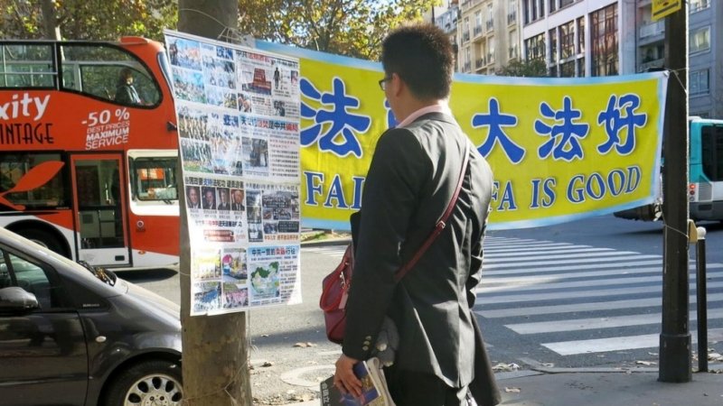 Туристы из Китая читают материалы о Фалуньгун