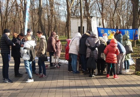 Гуляющие в парке с интересом столпились на месте проведения акции последователями Фалуньгун
