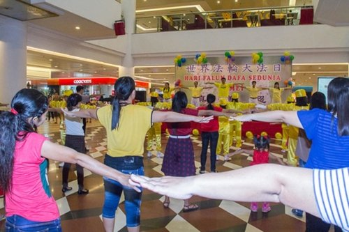 Практикующие обучают желающих упражнениям Фалунь Дафа в торговом центре, Индонезия