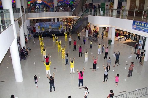 Практикующие обучают желающих упражнениям Фалуньгун в торговом центре и возле него, Индонезия