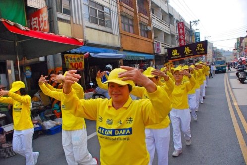 Последователи Фалуньгун во время парада демонстрируют упражнения