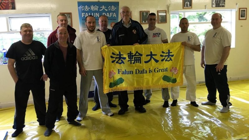 После обучения упражнениям учащиеся школы боевых искусств сфотографировались у плаката с надписью «Фалунь Дафа – великий» и выразили поддержку Фалуньгун
