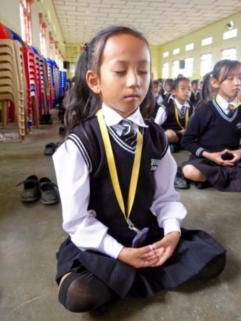 Девочка изучает пятое упражнение (созерцание в медитации) на занятиях, которые проводили практикующие Фалунь Дафа, рассказывая также и о преследовании этой практики в Китае