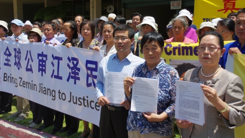 На митинге в Лос-Анджелесе последователи Фалуньгун Чжан Цзинь, Ли Шуин и Ши Чжэнхуа (слева направо) держат в руках копии исковых заявлений, поданных против Цзян Цзэминя, 2015 г.