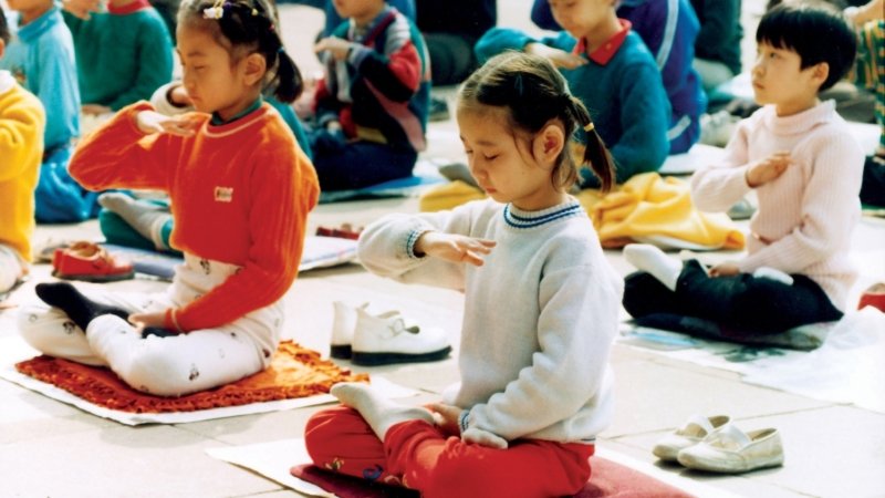 Юные последователи Фалуньгун выполняют медитативное упражнение