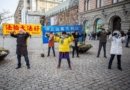 Практикующие выполняют упражнения на Монетной площади в Стокгольме. На жёлтом плакате написано «Фалунь Дафа – великий», на синем – «Остановить преследование Фалуньгун»