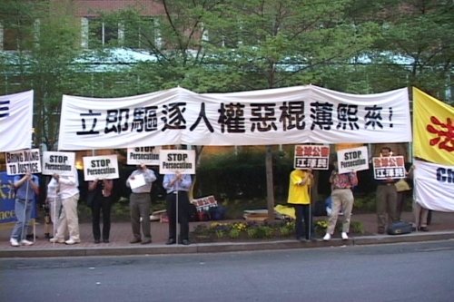 Практикующие Фалуньгун спокойно стояли в ряд, растянувшись от отеля Фэрмонт до оживленной улицы М, держа большие плакаты