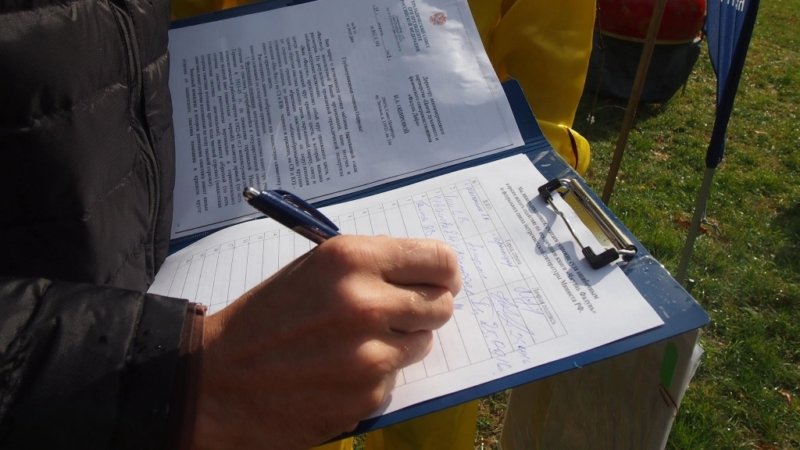 Люди подписывают петицию в защиту книги Фалуньгун во время презентации практики Фалуньгун. Краснодар, 2016 г.
