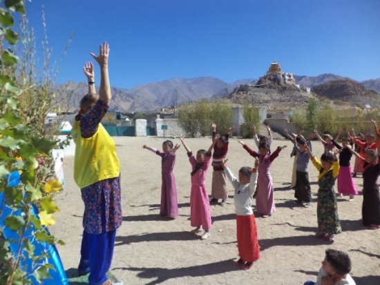 Под куполом голубого неба в Ладакхе практикующая Фалунь Дафа знакомит с этой практикой учеников школы, одетых в местные традиционные одежды