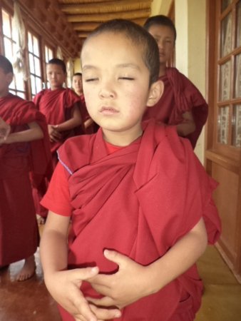 Мальчик изучает упражнения Фалунь Дафа во время самой маленькой презентации для восьми начинающих монахов