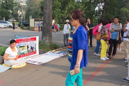 Последовательница Фалуньгун у плаката, призывающего к прекращению репрессий в Китае