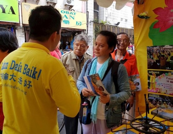 Туристы слушают практикующего, рассказывающего о практике Фалуньгун