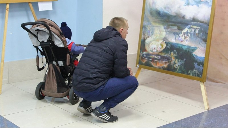 Посетитель внимательно рассматривает картину на выставке "Истина Доброта Терпение" в г. Ангарске, 2018 г.