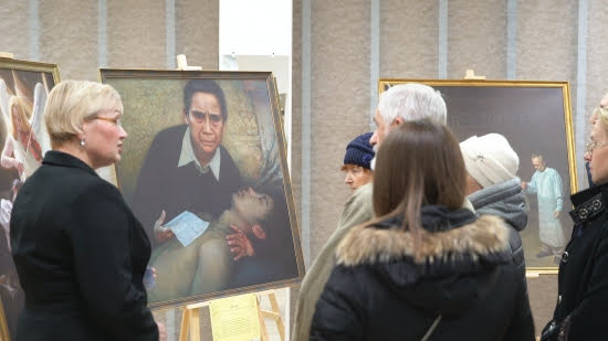 Гид рассказывает о картинах, изображающих страдания китайских последователей Фалуньгун от репрессий