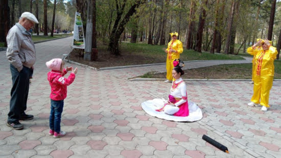 Маленькая девочка решила делать упражнения вместе с последователями Фалуньгун