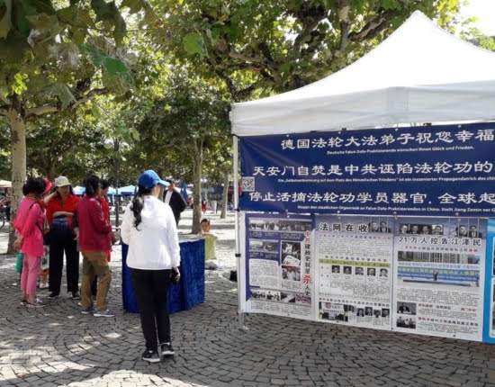 Китайские туристы читают плакаты с информацией о преследовании Фалуньгун в Китае