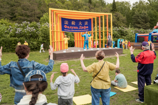 Зрители повторяют движения практикующих Фалуньгун, демонстрирующих упражнения