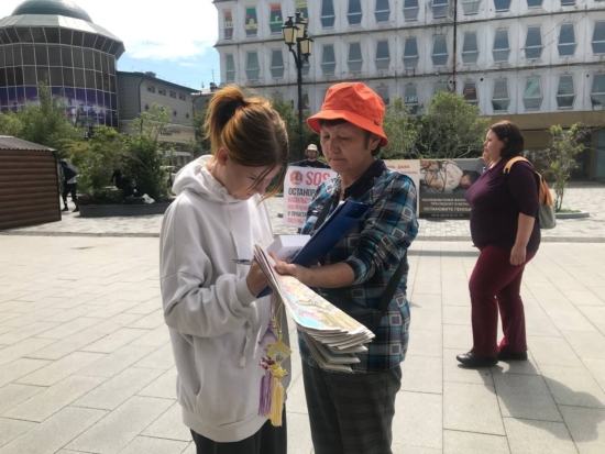 Девушка подписывает петицию против репрессий китайских практикующих Фалуньгун